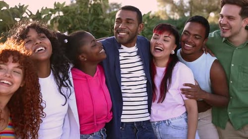 Young multicultural group of happy friends having fun together outdoors at sunset, smiling and laugh