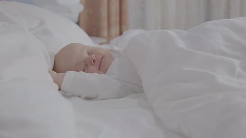 Infant Sleeping Peacefully Under a White Blanket