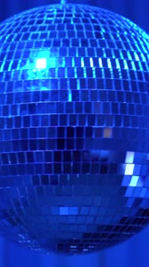 Brightly lit disco ball spinning at night. Vertical