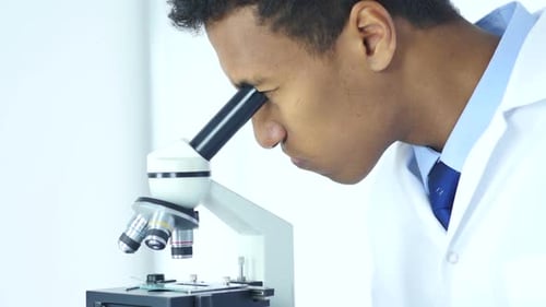 Man Using Microscope in Bright Lab Setting
