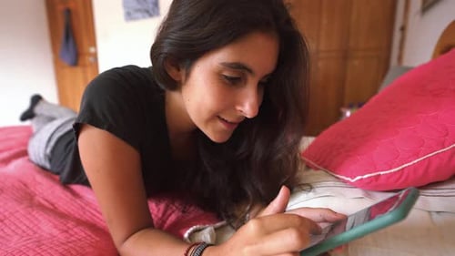 young Woman Lying On The Bed With Smartphone, Web Searching, swiping up.