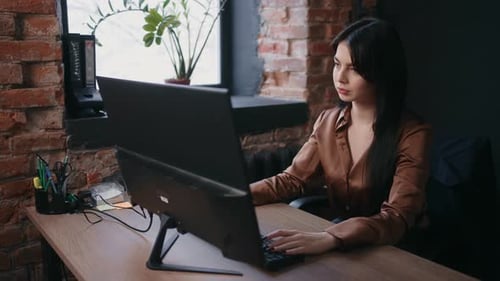 Schöne brünette Frau, die im Büro mit dem Computer arbeitet, Spezialistin für technischen Support, Porträt