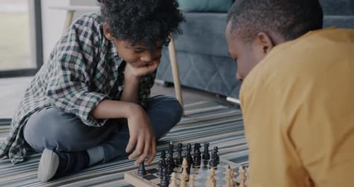 Child and Adult Playing Chess on Living Room Floor