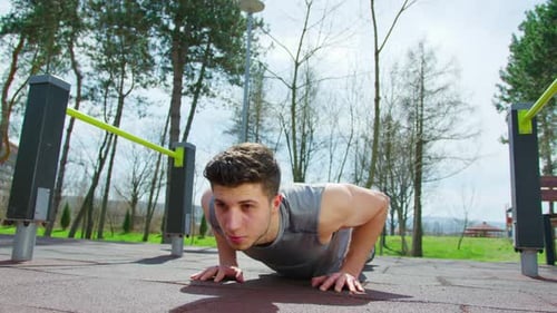 Joven haciendo flexiones en el parque
