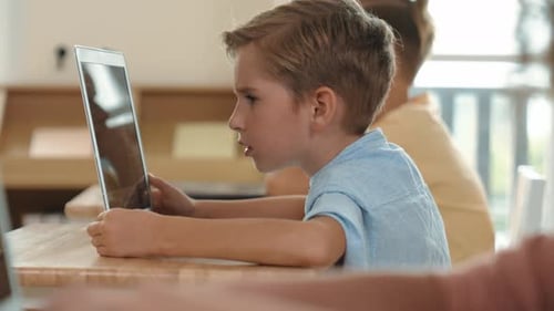 Side view of caucasian boy working on laptop while coding prompt. Pedagogy.