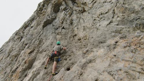 Man Climbing Up Rock as Girlfriend Holding Rope