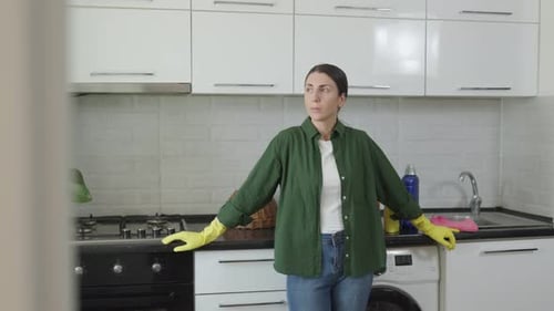 Woman Wearing Rubber Gloves in Kitchen Stands Still
