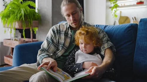 Father Reading Book With Child on Couch