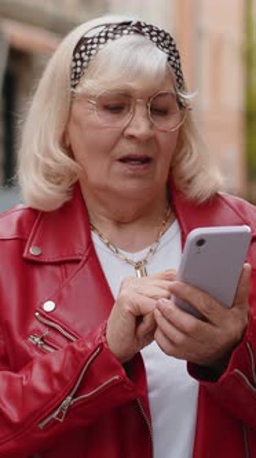 Senior Woman Use Smartphone Typing Text Messages Browsing Internet Finishing Work Looking at Camera