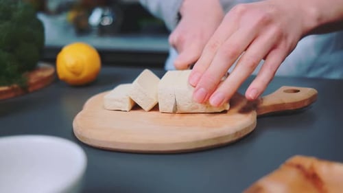 Hands Slice Block of Tofu on Cutting Board