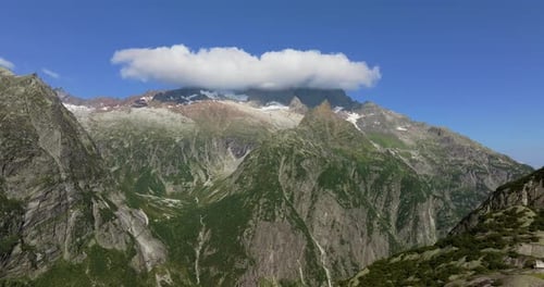 Alpine landscape featuring towering granite peaks and lush green slopes under a vivid blue sky,