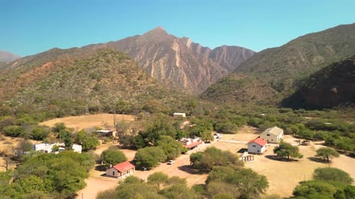 Aerial view drone flying over little village with mountains landscape and clear blue sky.
