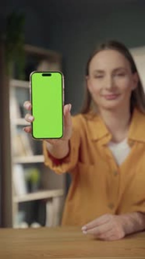 Woman Holding a Modern Smartphone with a Vivid Green Screen Offering a Crisp Customizable Display