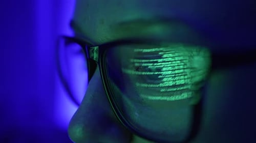 Mujer analista o programadora trabaja en una computadora con anteojos de cerca