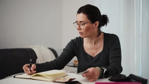 Woman Counting Money and Taking Notes at Home
