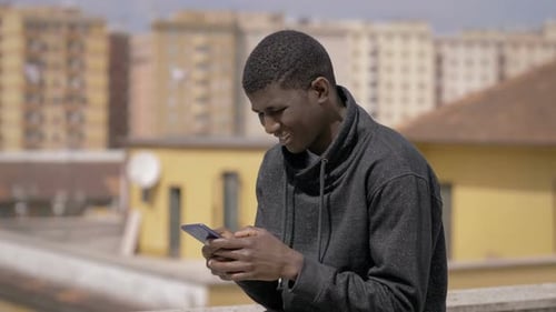 modern Young Black Man Using Smartphone Standing on Building roof