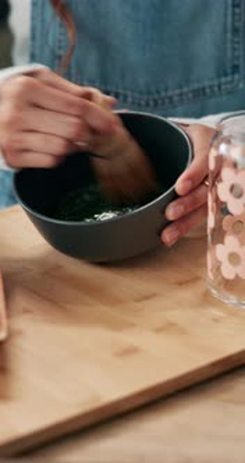 Woman Mixing Green Liquid in Bowl with Whisk