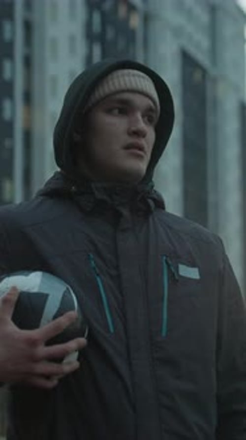 Young Man Holds Soccer Ball in Urban Setting