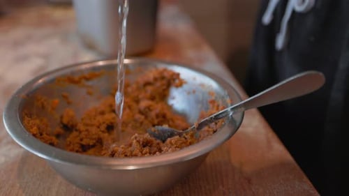 Water Pouring Into Food in Metal Bowl