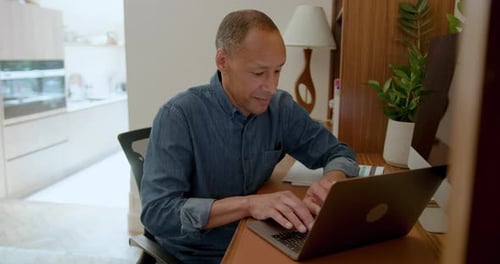 Mature Male Working on a Laptop in his Home office