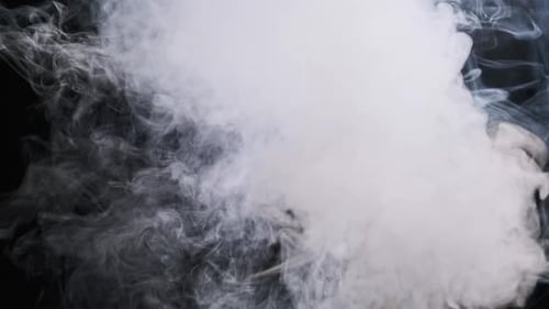 Humo blanco sobre un fondo negro en una explosión de vapor en cámara lenta