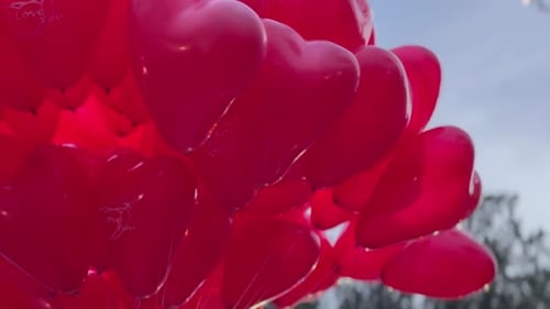 Vibrant Red Heart Balloons Swaying in the Breeze