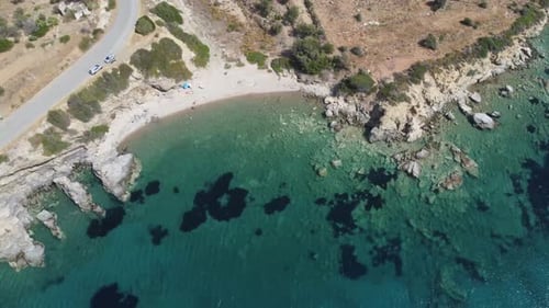 Aerial Drone Establishing Beach shot in Greece. Rocky beach with shallow water.