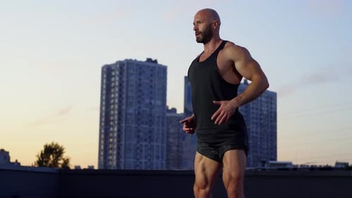 Man Doing Squats on Rooftop at Sunset