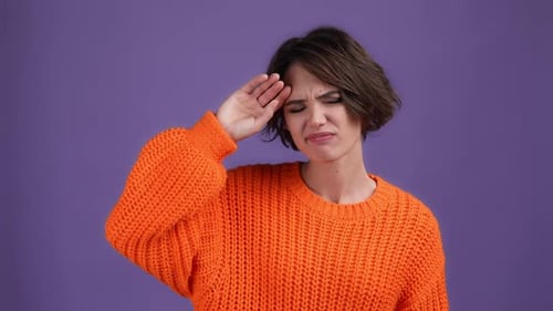 Femme mécontente en pull rouge tapant des mains dans le studio violet
