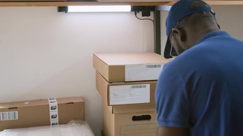 Black Male E-commerce Warehouse Employee Preparing Parcels for Shipment