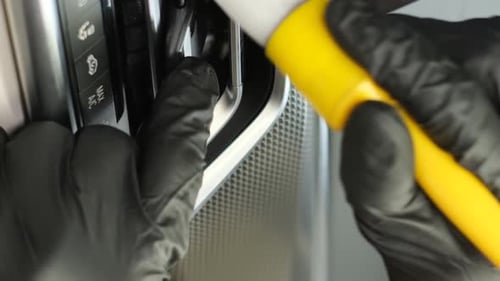 Gloved Detailer Cleaning Car Console With Brush