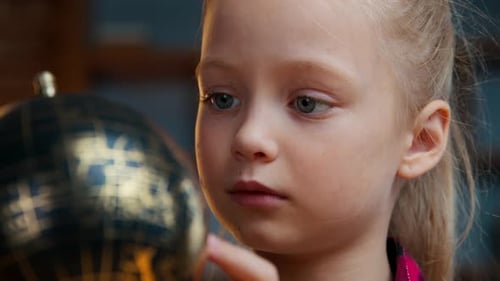 Close Up Little Caucasian Child Kid Girl Daughter Rotating Gold Globe Studying at Evening Home Baby
