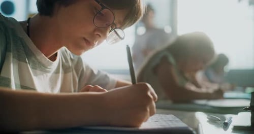 Elementary School Boy Writing Exam or Doing Task in Notebook