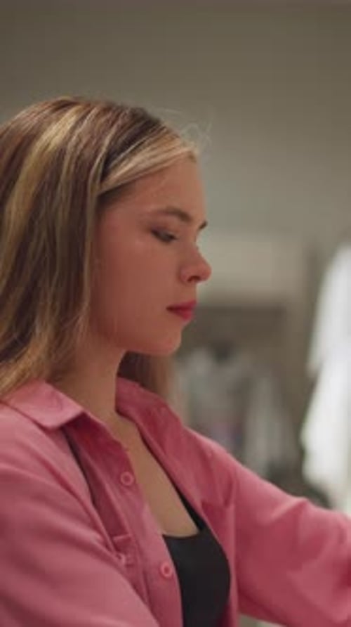 Lady in Pink Dress Examining White Shirt in Clothing Store
