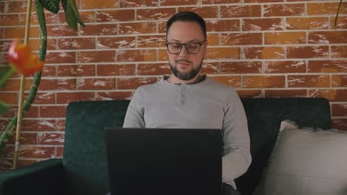 Man Using Laptop on Sofa at Home