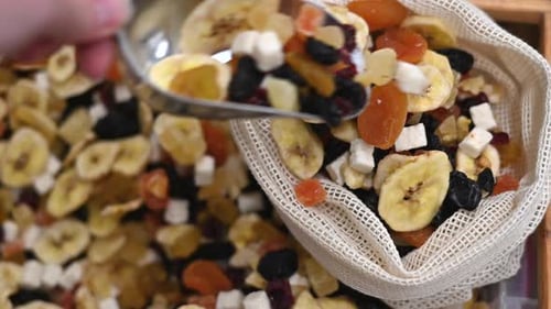 A person picking dried fruits in a reusable bag in a store. Ecology and Earth Day thematics. Slow mo