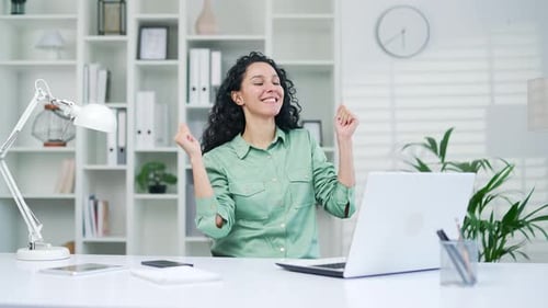 Happy joyful young hispanic woman office worker completed work on project dancing in the workplace F
