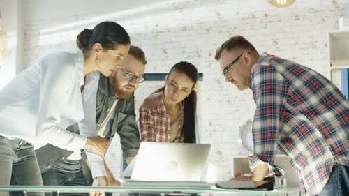 In Creative Office Productive Coworkers Standing around Table Having Strategic Planning Session. Th