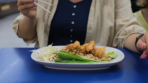 Young Woman Eating Pad Thai with Shrimps Indoors
