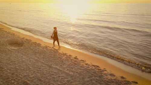 Fit Woman with Exercising Mat in Hands Walking Barefoot at Sunset Sea Beach Before Fitness Training