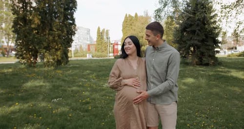 Un jeune couple attend un enfant passant du temps dans un parc d'été