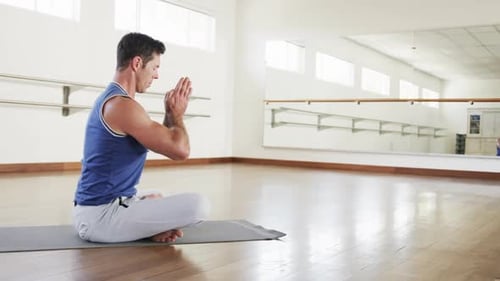 Focused caucasian man practicing yoga meditation in gym, slow motion