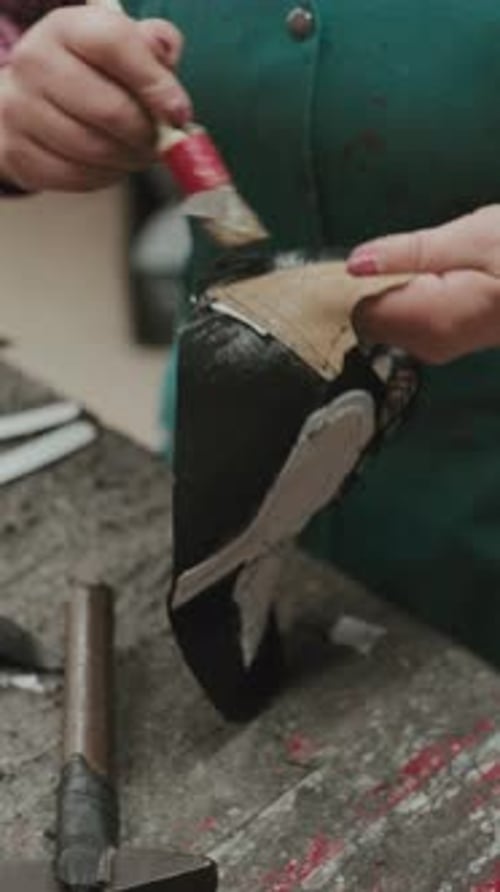Woman Carefully Glues Leather Piece onto Shoe
