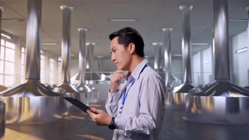 Asiatischer männlicher Arbeiter benutzen ein Tablet in einer Bierfabrik