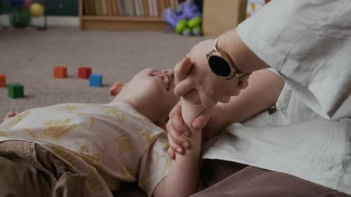 Une mère renforce les muscles de la main de son fils handicapé à la maison