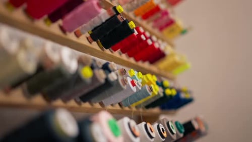 Closeup in Sewing Workshop of Different Colors of Skeins of Thread on a Stand on the Wall
