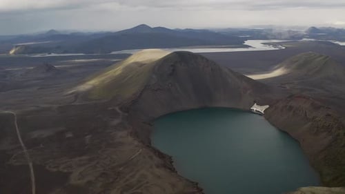 Ascending push shot of crater lake surrounded by volcanic landscape during clouds at sky