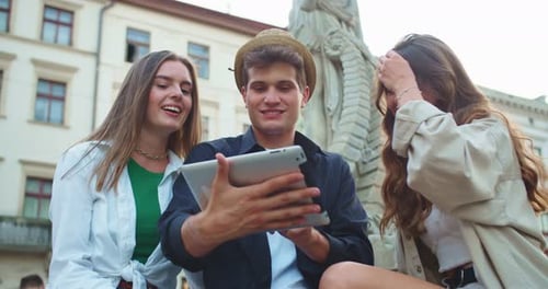 Portrait of Happy Caucasian Friends Outdoors in City Handsome Male Tapping and Browsing on Tablet