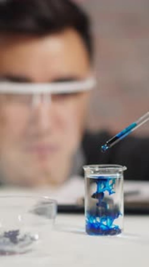 Un scientifique expérimenté ajoute un liquide bleu à de l'eau claire lors d'un test