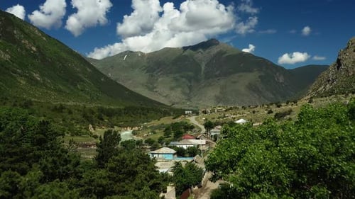 Aerial View of a Mountain Range with a Village in the Foreground and a Pool in the Middle